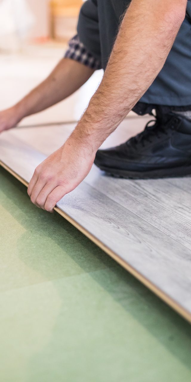 Young worker laying a floor with bright laminated flooring boards