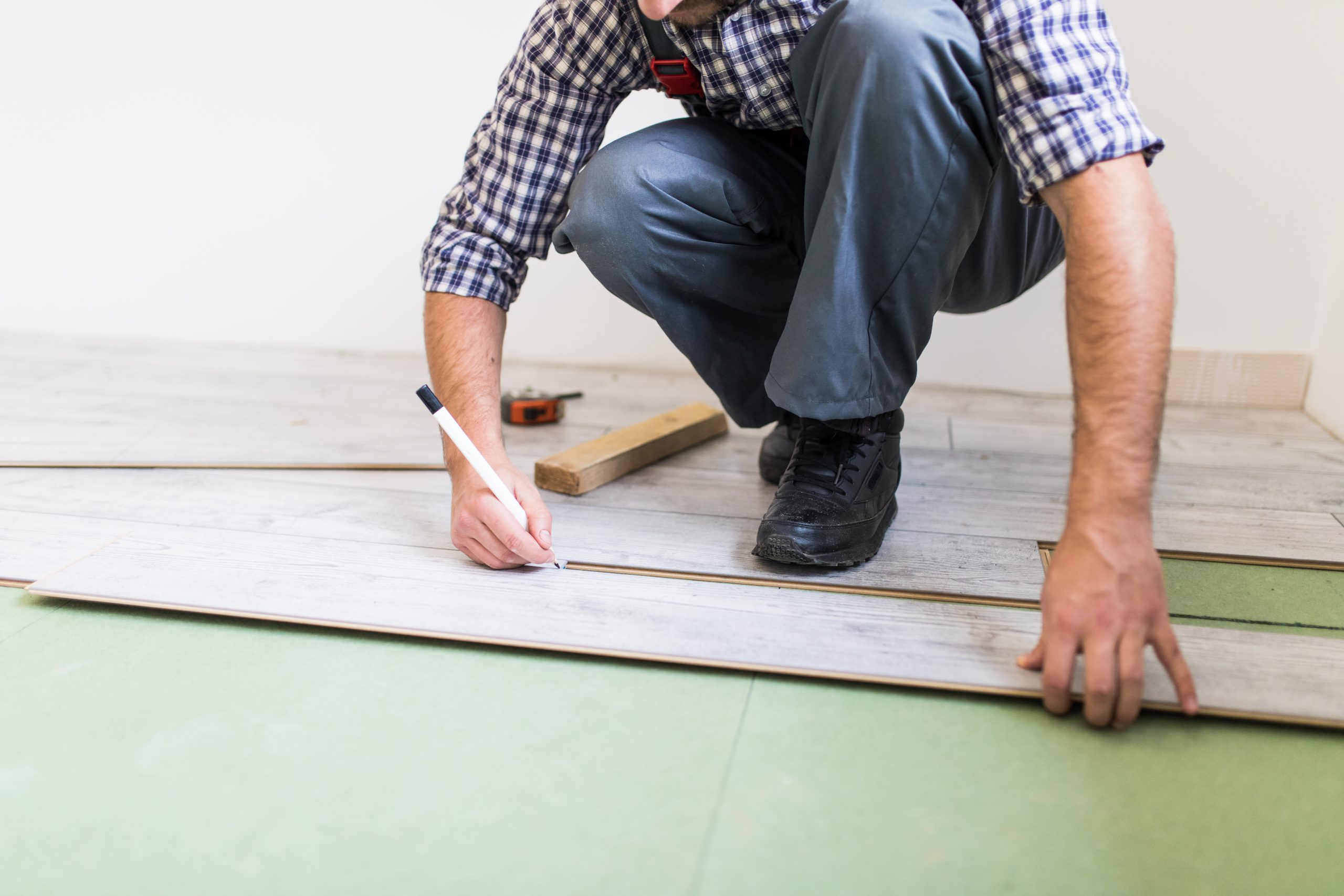 Young worker laying a floor with bright laminated flooring boards